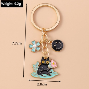 Detail view of cartoon black cat keychain with pink lotus charm and gold metal finish