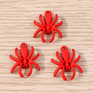Detail of red spider charms with matte finish for DIY jewelry on light wood background