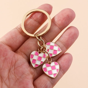 Detailed macro view of three pink checkerboard heart pendants on a gold keychain ring