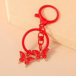 Detail of red enamel butterfly keychain with lobster clasp and gold-tone metal edges