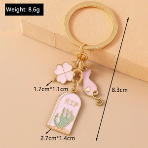 Detailed view of a gold-toned keychain with pink enamel charms and size measurements