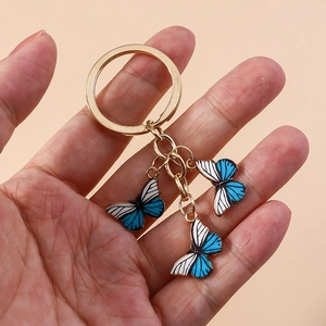 Porte-clés papillon tendance avec breloques rayées bleues et blanches sur anneau doré