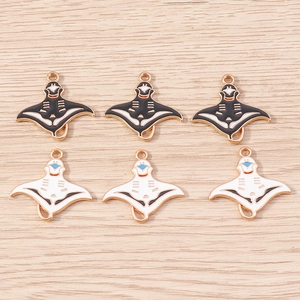 Detailed view of DIY manta ray enamel pendants in black and white on a wooden background
