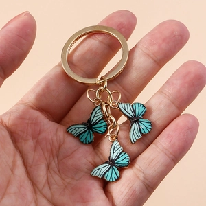 Détail des pendentifs papillons bleu sarcelle avec textures noires et chaîne dorée