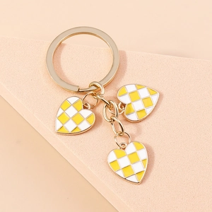 Detailed close-up of yellow and white checkered enamel heart charms on a gold keychain
