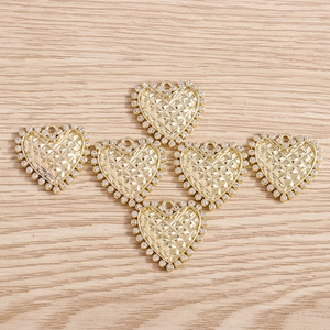 Detail of six heart-shaped rhinestone pendants in gold with diamond-cut pattern and hanging holes