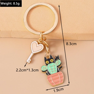 Detail of cute cat cactus and heart key enamel pendants on golden metal keychain