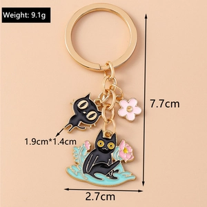 Detail of cute black cat keychain with pink flower charms and golden metal keyring