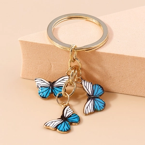 Détails de charms papillon en émail bleu et blanc avec anneau porte-clés doré