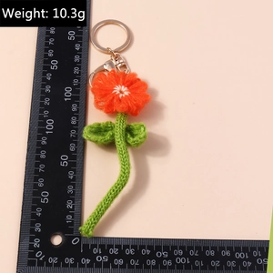 Vue détaillée du porte-clés fleur de prunier tricoté orange avec fermoir métallique