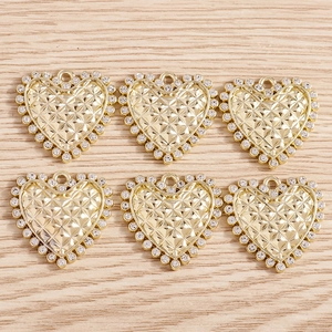 Quilted gold heart pendants with white rhinestones on light wood background for DIY jewelry