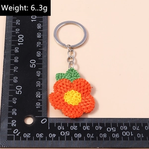 Détail macro du porte-clés fleur crocheté main avec mesures sur règle graduée