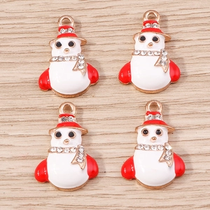 Macro detail of snowman charms with red enamel hats and sparkling crystals set on wood