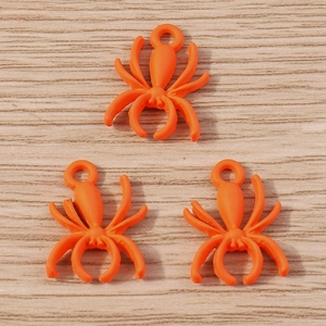 Detailed view of three bright orange spider charms with top loops for DIY jewelry projects