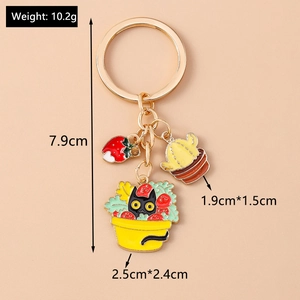 Detailed view of 7.9cm golden keychain with cartoon cat, cactus, and strawberry charms