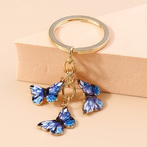 Détail d'un porte-clés doré orné de trois pendentifs papillons dégradés bleu et violet