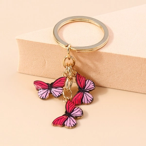 Détail de trois pendentifs papillons en émail rose sur un porte-clés doré élégant
