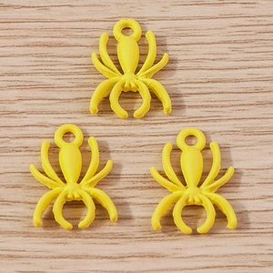 Detailed close-up of three bright yellow spider-shaped alloy pendants for jewelry DIY