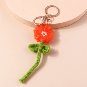 Détail d'un porte-clés fleur orange crocheté à la main avec feuilles vertes et anneau doré