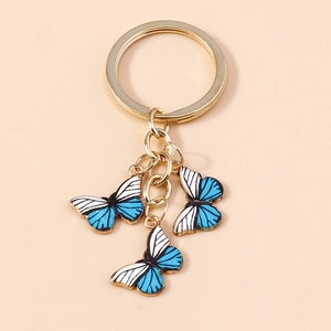 Détail du porte-clés papillon à rayures bleu et blanc avec anneau doré pour sacs