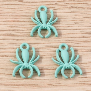 Macro shot of mint blue spider charms for DIY jewelry making on a wooden background