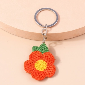 Détail d'un porte-clés fleur de prunier crocheté main avec pétales orange et feuille