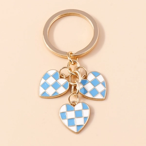 Close-up of golden keychain with blue and white checkered heart charms on beige background