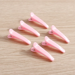 Detailed view of six pink professional hair sectioning clips on a wooden surface