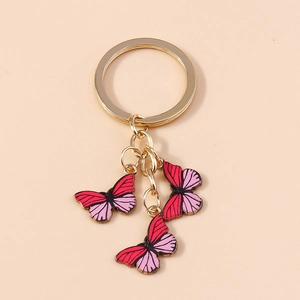 Vue détaillée de trois breloques papillon rouge et rose sur un porte-clés doré chic