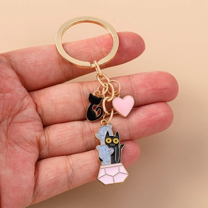 Detailed close-up of a golden alloy enamel keychain featuring cute black cat and heart charms
