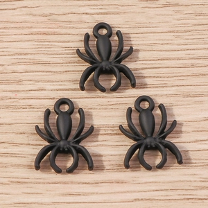 Detailed view of three matte black spider charms with top loops for DIY jewelry
