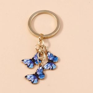 Détail macro d'un porte-clés doré avec des breloques papillons dégradées bleu et violet