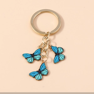Vue détaillée de trois papillons en émail bleu sur un porte-clés en métal doré chic