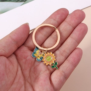 Detail of sunflower and rainbow butterfly enamel charms on a golden keychain ring