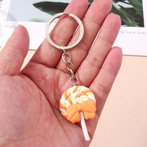 Detail of a candy lollipop keychain with orange bow and silver ring held by hand