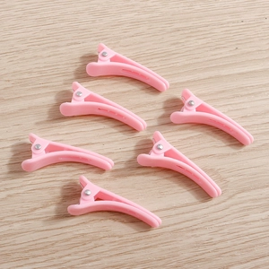 Set of 6 cute pink plastic duckbill hair clips on light wood background for women hair styling
