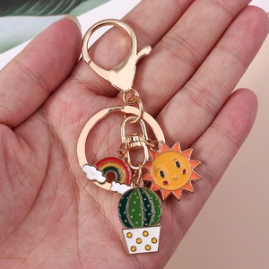 Golden keychain with cartoon rainbow cloud, smiling sun and cactus charms for bags