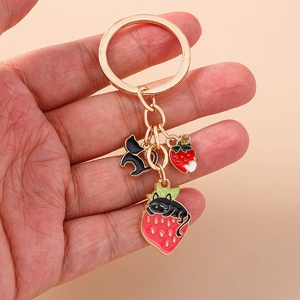 Detail of cute black cat and strawberry charms on a gold-plated alloy keychain