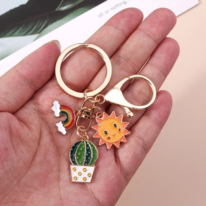 Detailed view of enamel keychain charms featuring a cactus, sun, and rainbow motifs