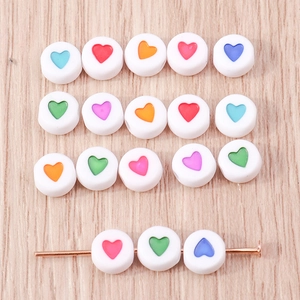 Dettaglio di perline in acrilico bianco con cuori colorati per creazione gioielli DIY
