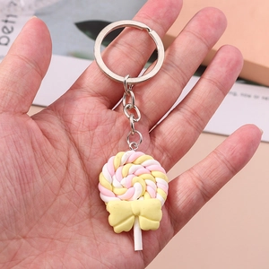 Fashionable pink and yellow lollipop keychain with a bow being held in hand