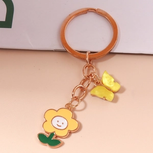Detail of rose gold keychain with smiley sunflower and yellow butterfly pendants