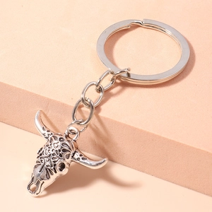 Detail of vintage silver bull skull keychain with intricate hollowed patterns and turquoise