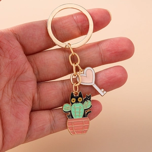 Detail view of gold enamel keychain featuring heart-shaped pendant and cute cactus cat charm