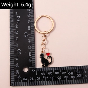 Détails d'un porte-clés chat en émail noir avec cœur rouge et anneaux en métal rose