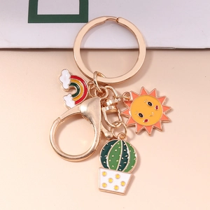 Detailed view of colorful sun, rainbow, and cactus enamel pendants on a gold keychain