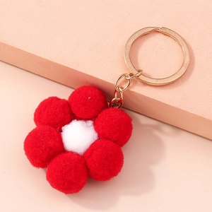 Close-up of a plush red flower keychain with a gold ring for backpacks and handbags