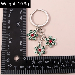 Porte-clés flocon argenté avec bords verts et strass rouges près d'un outil de mesure