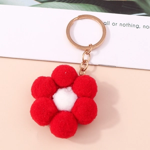 Detail of plush red flower keychain with soft pom-poms and gold metal ring