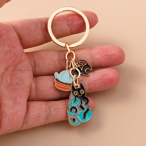 Detail of alloy cartoon cat and cactus keychains with gold chain held by hand